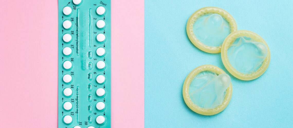 Contraceptive pills and condoms on colored background. View from above. Concept of birth control